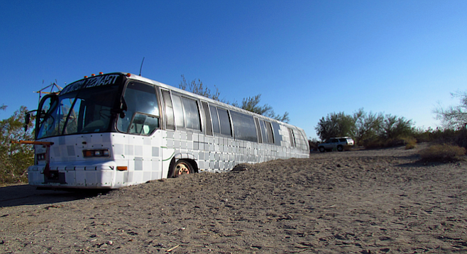 A half-buried bus named Walter greets visitors to East Jesus, a self-sustaining art community in the Southern California desert.